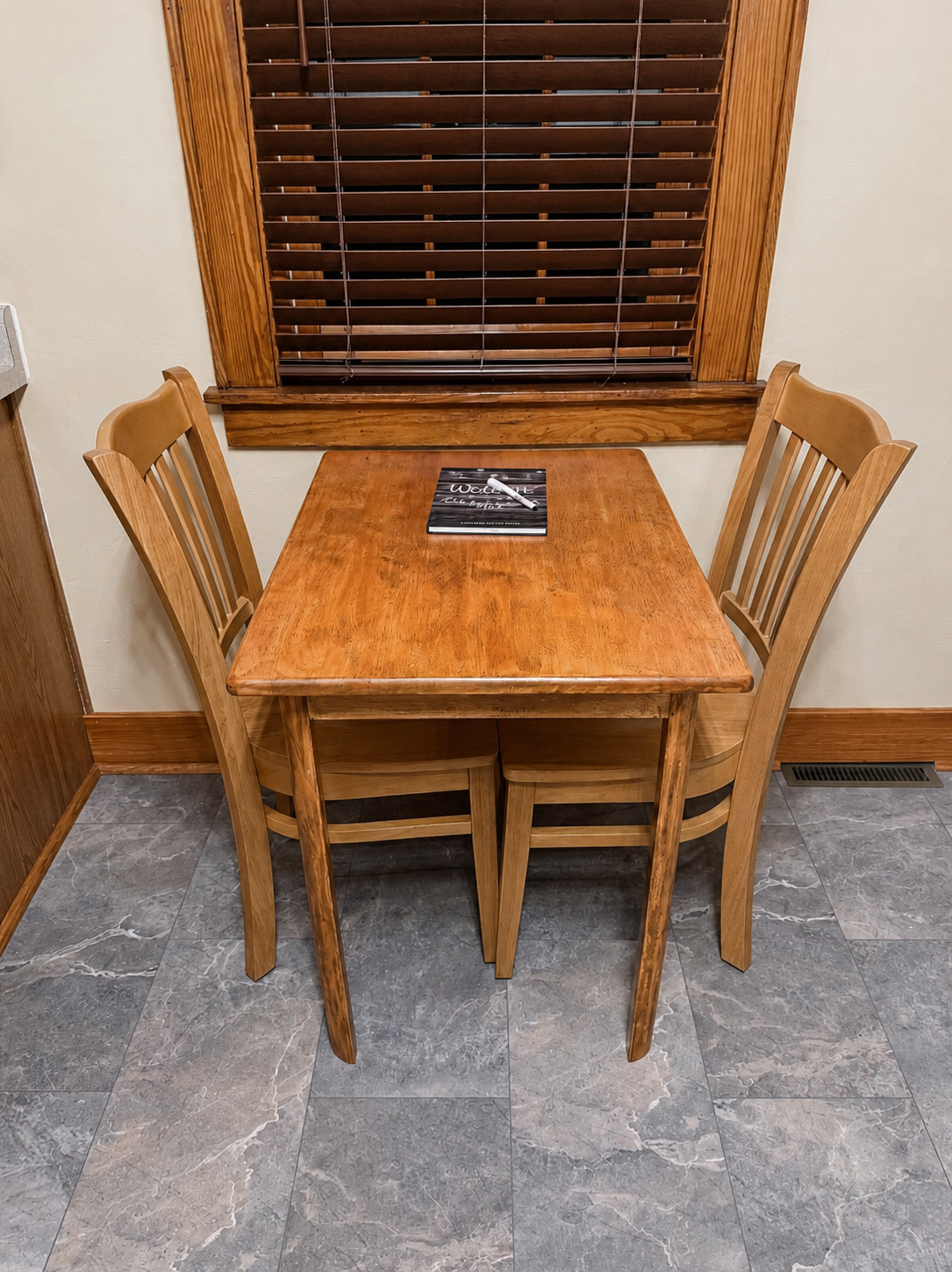 Compact dining nook with a wood table and two chairs beneath a window